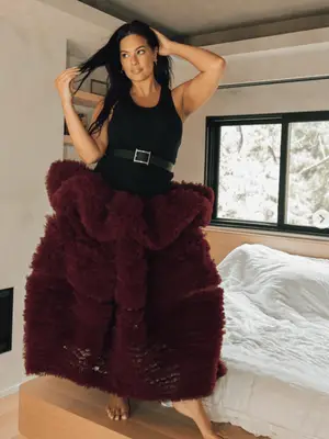 Ashley Graham wearing a black top and burgundy tulle skirt
