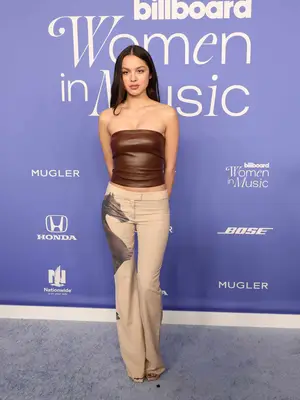 Olivia Rodrigo wearing a strapless brown leather Chloe top and trousers with a horse design
