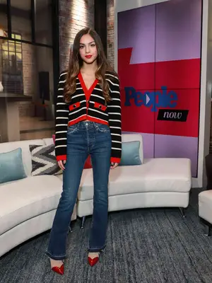 Olivia Rodrigo wearing a striped cardigan with a pair of flare jeans and pointed-toe heels