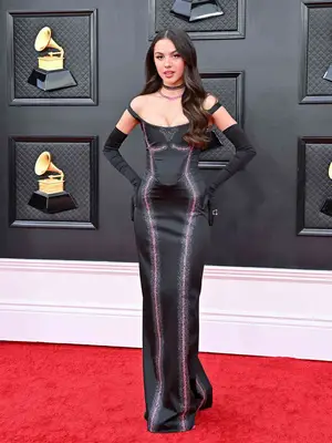 Olivia Rodrigo at the Grammy Awards wearing a black off-the-shoulder Vivienne Westwood gown with black opera gloves