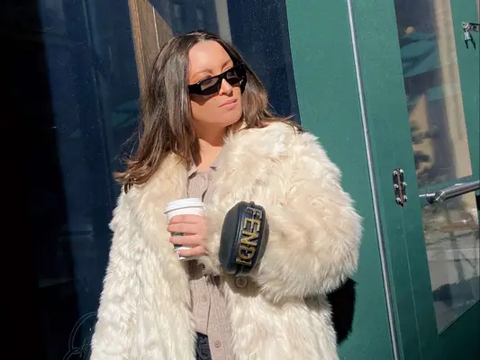 MYM Beauty writer Bella Gerard wears a black Fendi bracelet bag, sunglasses, and cream fur coat