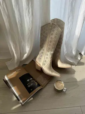 Still live of floral cowboy boots, open coffee table book, and cup of coffee