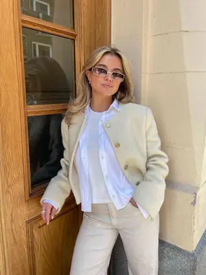 Matilda Djerf wears a white t-shirt, button-down, and cream cardigan and pants, plus sunglasses