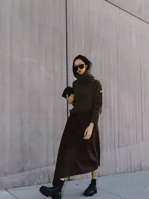 Chriselle Lim wears a turtleneck sweater, slip skirt, platform ankle boots, shield sunglasses, and black handbag