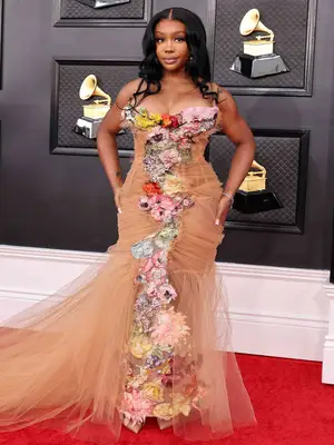 SZA wears a tan tulle Jean Paul Gaultier gown with floral detailing to the 2022 Grammys red carpet