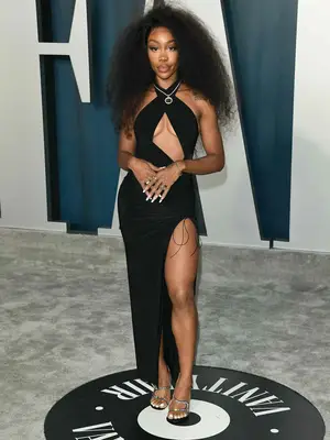 SZA wearing a black cut-out dress, black sandals, and a statement necklace to the 2020 Vanity Fair Oscars afterparty