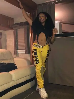 SZA wearing a black bodysuit with yellow graphic pants and white sneakers