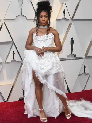 SZA wearing a white Vivienne Westwood white floral ballgown with a high-low silhouette, a diamond choker, white sandals, and updo hairstyle