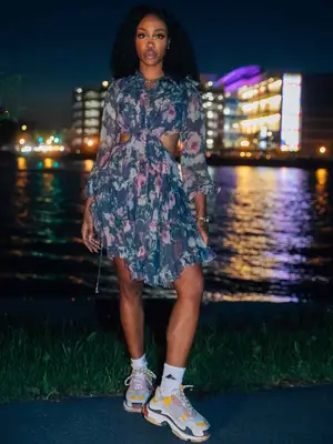 SZA wearing an iris floral open-back silk dress, multicolored sneakers, and crew socks