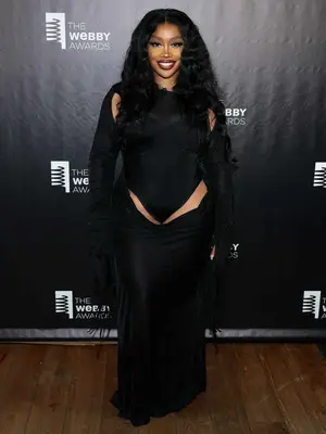 SZA wearing a black dress with cutouts on the shoulders and upper thighs 