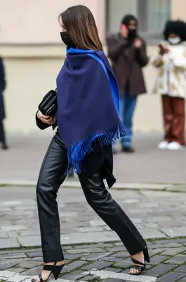 Woman wearing a navy blue and electric royal blue cashmere fringed scarf, black leather cigarette pants, a black leather handbag, black strappy heels, and a face mask 