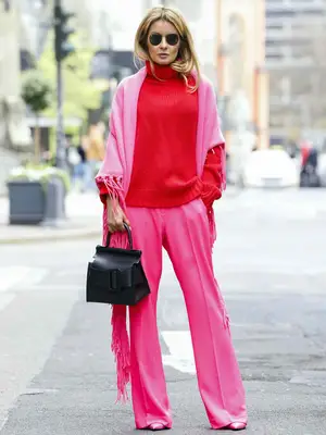 Gitta Banko wearing a red oversize cashmere turtleneck pullover by Simone Bruns, a pink scarf with fringe detail by Simone Bruns, pink pants by Dea Kudibal, pink pumps by Balenciaga, a black bag by Boyy and sunglasses by Ray-Ban