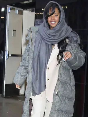 H.E.R. wears a gray jacket, a white blazer and trousers, and a blue-gray scarf wrapped around her head