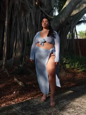 Nadia Aboulhosn wearing a baby blue long sleeve crop shirt and a maxi skirt, gem necklace, and sandals