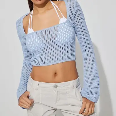 Model wearing a square neck baby blue crop sweater over a white bikini with white shorts 