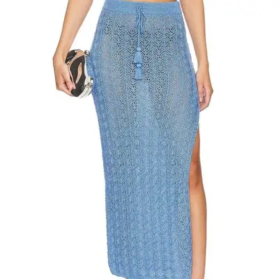 Model wearing a blue crochet maxi skirt and holding a silver clutch 