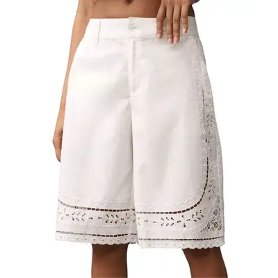 model wearing white short trousers with eyelet cutouts