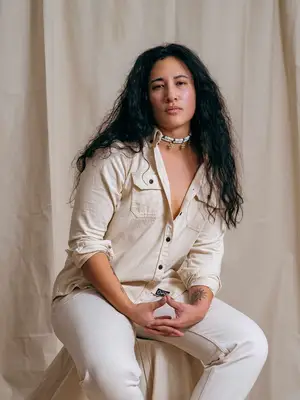 Person wearing off-white button-down shirt, white jeans, and layered necklaces