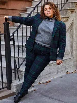Person wearing gray zip-up top, blue and green plaid suit, and black loafers
