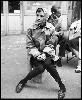Audrey Hepburn wears a head scarf, trench coat, skinny pants, and loafers