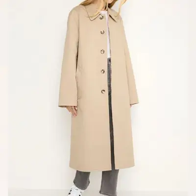 model wearing khaki trench coat against plain background