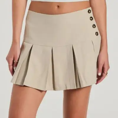model wearing khaki pleated tennis skirt with buttons on the side