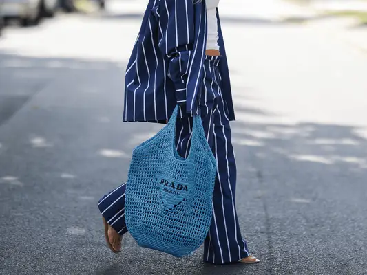 woman carrying blue raffia prada tote