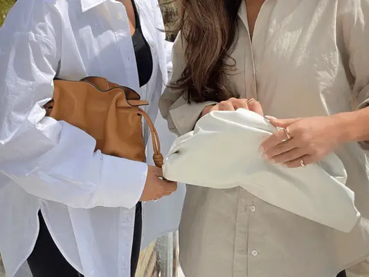 two women holding slouchy leather bags