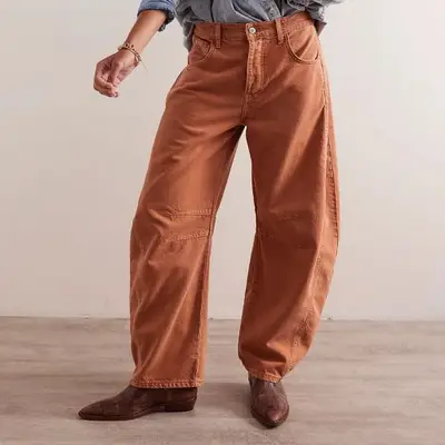 model wearing orange free people barrel jeans with brown boots