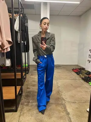 Sarah Brody wears a blazer, blue wide leg pants, and black pointed-toe heels