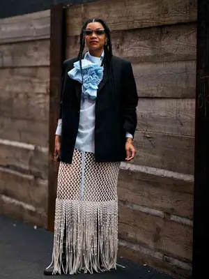 Sherri McMullen wears a light blue blouse, black blazer, white crocheted maxi skirt, and sunglasses