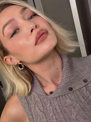 Gigi Hadid wears a sleeveless knit top and gold earrings