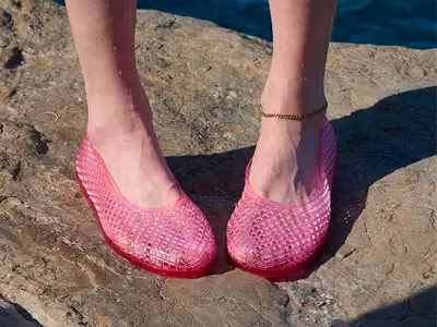 Feet wearing gold sandals with decorative yellow and pink floral designs