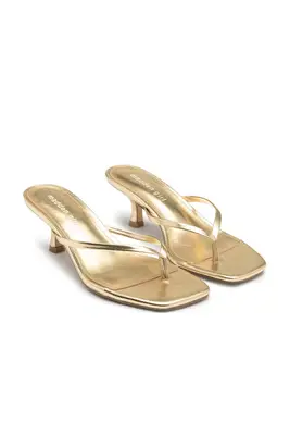 Madden Girl gold heeled flip flops against a white background.