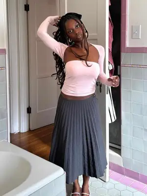 Toni Bravo wearing a pink top and shrug with a long gray pleated skirt