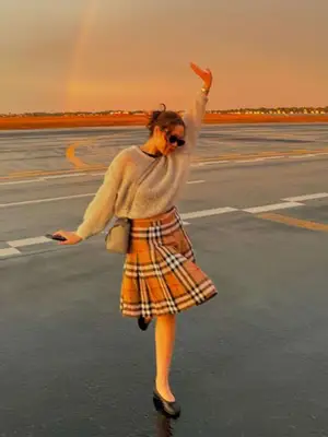 Laufey posing for a photo with a plaid skirt and sweater