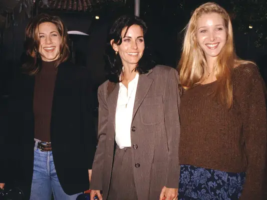 Jennifer Aniston, Courteney Cox, and Lisa Kudrow wearing neutral fall outfits