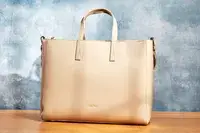 The calpak haven laptop tote bag on a wooden table