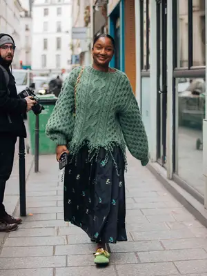 Person wearing a green sweater and printed skirt