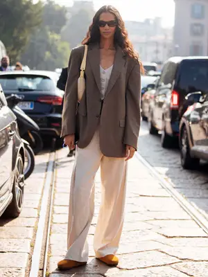 Model wearing a blazer, button-down cardigan, pants, and clogs