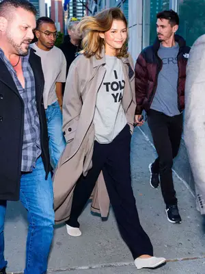 Zendaya wearing a gray t-shirt, wide leg pants, a gray trench coat, and ballet flats