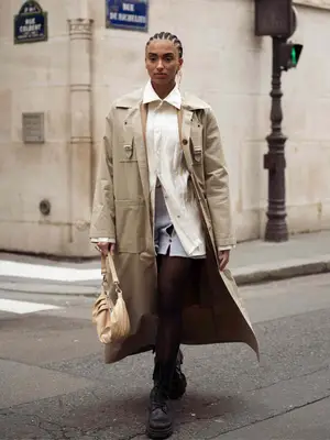 Woman wearing a button-down blouse, mini skirt, trench coat, and chunky boots