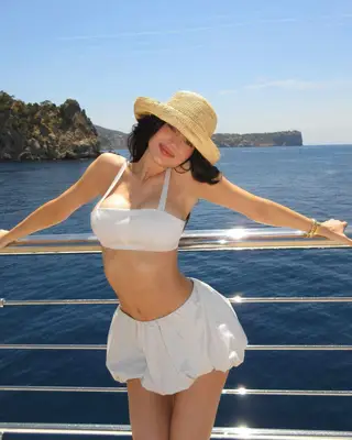 Kylie Jenner wearing a white bubble mini skirt with a white bra-style top and woven sun hat
