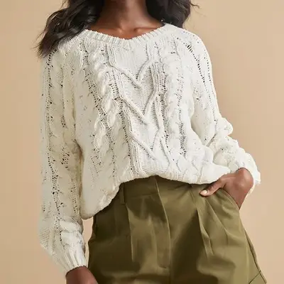 Close up of a model wearing a white knit sweater 