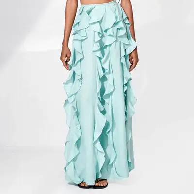 Model waring a long blue-green skirt with ruffles 