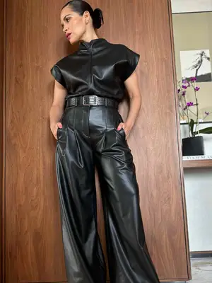 America Ferrera wears a leather top tucked into oversized leather pants and bun hairstyle