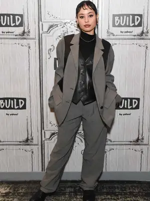 Alexa Demie wearing black leather vest and gray oversized pantsuit