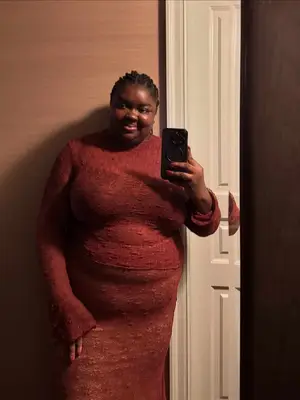 Woman wearing a red textured top and matching skirt taking a mirror selfie