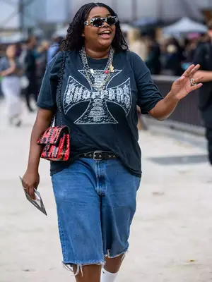 Gabriella Karefa-Johnson wears a choppers graphic tee, denim bermuda shorts, Chanel bag, silver jewelry, and sunglasses