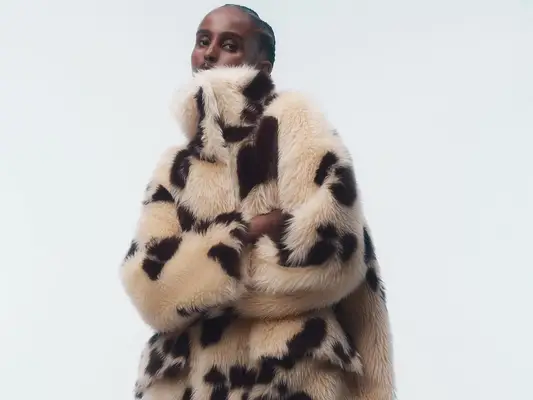 Model wearing furry, spotted Stand Studio coat with arms crossed